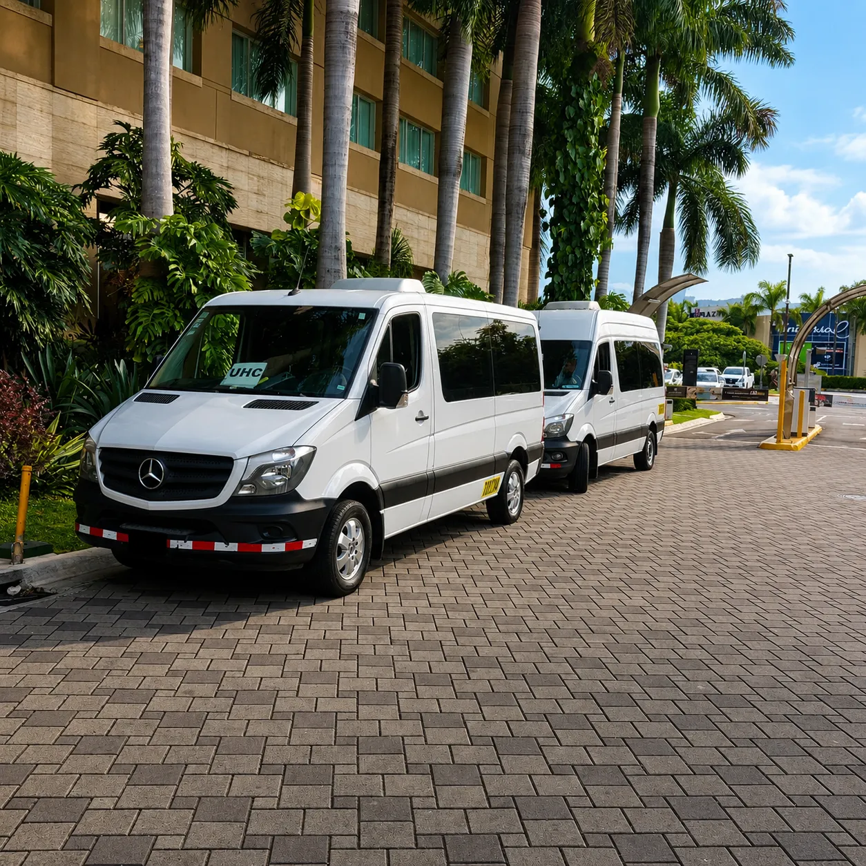 Dos microbuses blancos frente a un hotel.